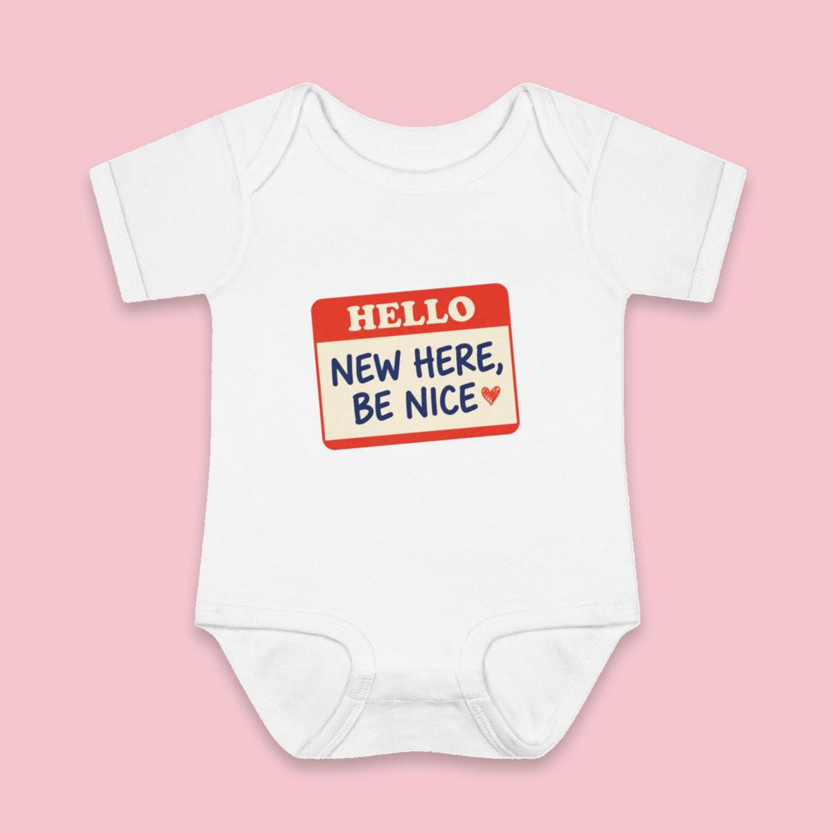 New Here, Be Nice onesie – Flat on pink background